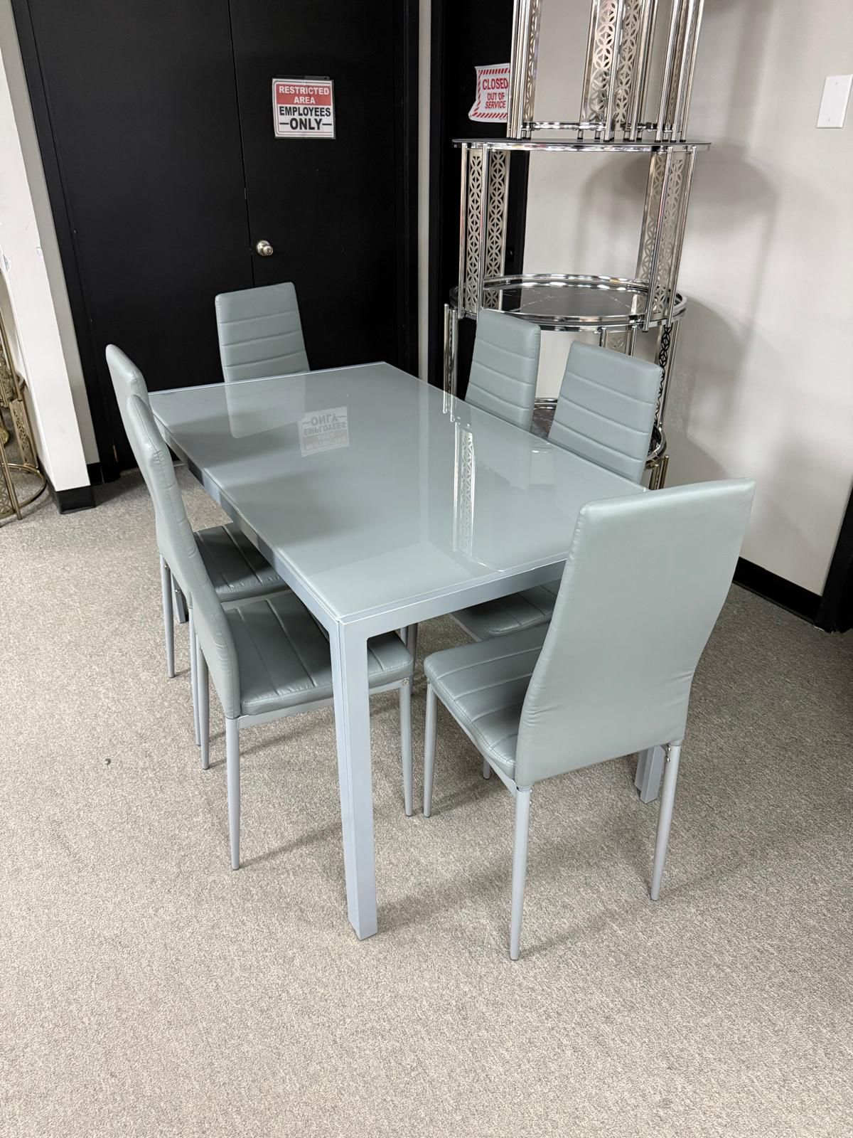Grey glass-top dining table with 6 grey upholstered chairs