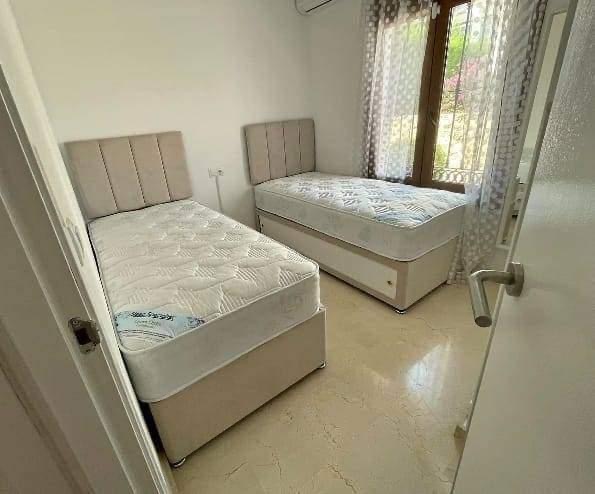 Two twin beds with beige channel-tufted headboards in bedroom